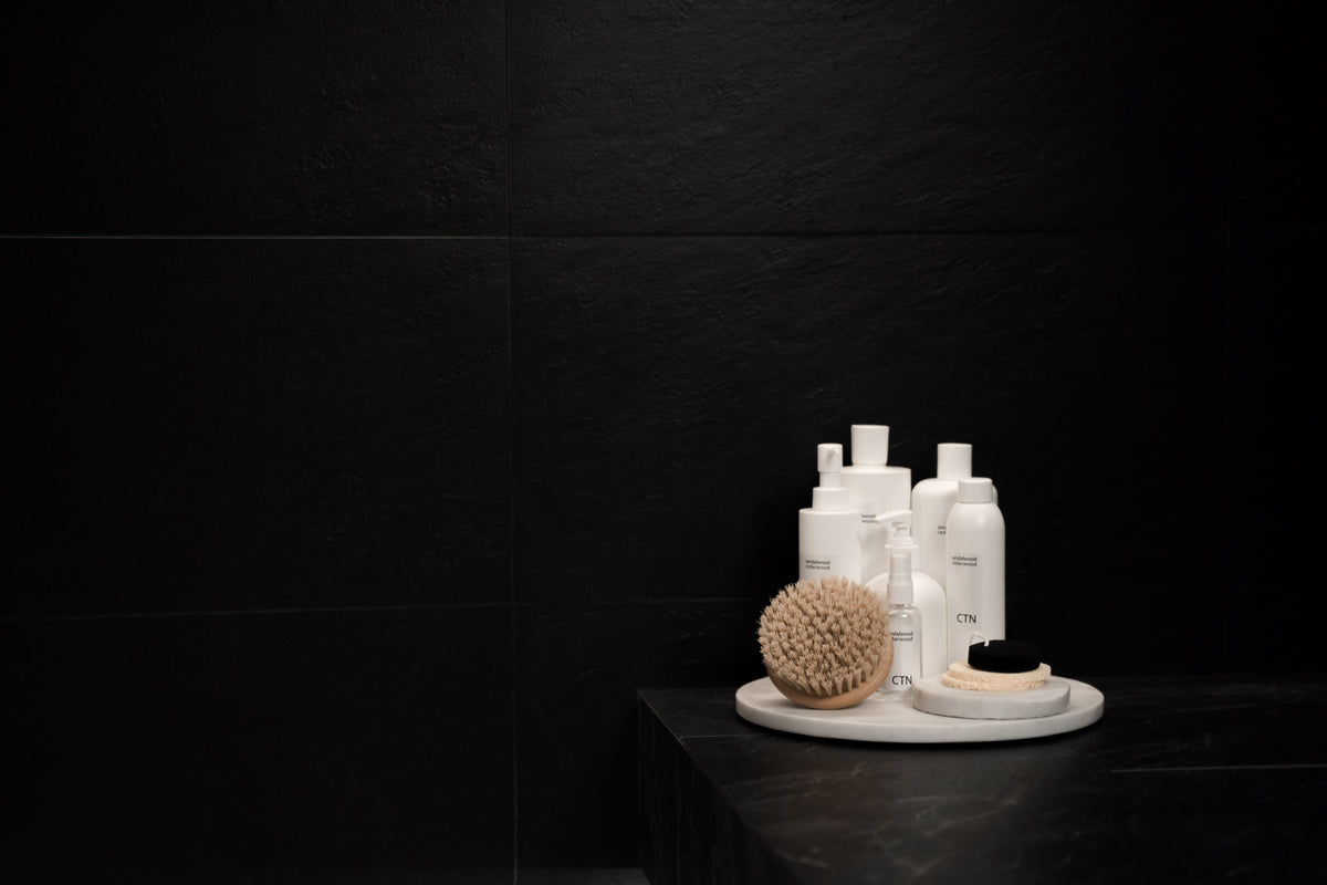 Cosmetic bottles and a dry brush on a dark surface