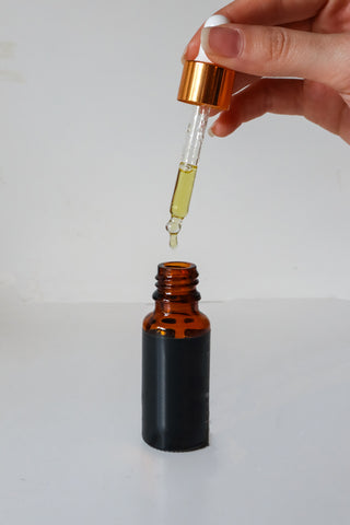 Hand holding a small dispenser above a vial